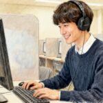 ヘッドホンをして、パソコンで英語の文章を打っているスーツマンのイラスト（英検S-CBTの会場のイメージ）
